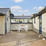 Hinterhof mit Tisch, Stühlen und Satellitenantenne. Beide Seiten sind mit Holz verkleidet.