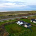 Haus mit Garten, Straße und Meer im Hintergrund.