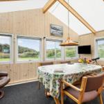 Esszimmer mit Holzwand, Tisch mit Tischdecke und Fensterblick auf Grünflächen.