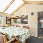 Essbereich mit Tisch, Stühlen und Blick auf Grasland. Küche ist über Tür sichtbar.