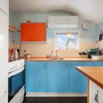 Küche mit blauen Schränken, orangefarbenem Oberteil und Kücheninsel.