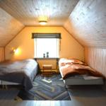 Zwei Betten in einem Dachzimmer mit Holzwand und Fenster