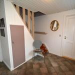 Eingangsbereich mit Stufen, Stuhl und Spiegel an der Wand.