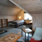 Schlafzimmer mit Holzwand, Bett, Sofa und Tisch.