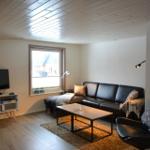 Wohnzimmer mit Sofa, Couchtisch und Fernseher an der Wand.