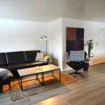 Wohnzimmer mit Sofa, Sessel, Couchtisch und Wandbild.