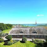 Dorfhaus mit Strohdach und Garten. Blick auf Wasser und Wiesen.