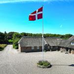 Traditionelles Dänemarkhaus mit Strohdach und dänischer Flagge auf dem Hof.