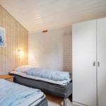Zwei Betten, weiße Schrankwand und Holzwand im Schlafzimmer.
