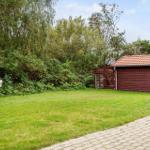 Grüner Garten mit Steinweg und rotem Holzschuppen im Hintergrund.