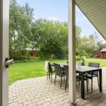 Terrasse mit Tisch und Stühlen, Blick auf grünen Garten und roten Schuppen.