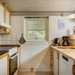 Küche mit Kühlschrank, Herd und Spüle an weißer Ziegelwand.