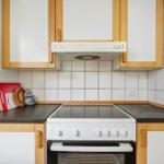 Küche mit Holzschränken, Induktionskochfeld und weißen Schränken.