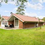 Ein Haus mit Terrasse, Grill und Schaukel im Garten.
