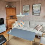 Wohnzimmer mit Sofa, Couchtisch und Fernseher. Holzwände und Bilder an der Wand.