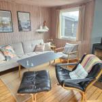 Wohnzimmer mit Sofa, Sessel und Kaminofen an Wand.