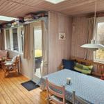 Essbereich mit Tisch, Stühlen und Fensterblick. Holzdecke, Boden und Wände.