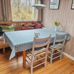 Esszimmer mit Holztisch, Stühlen und Fensterblick auf Grasland.