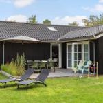 Schwarzes Haus mit Terrasse, Liegestühlen und Garten.