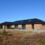 Moderne Villa mit Solaranlage und großem Terrassenbereich im Freien.