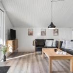 Wohnzimmer mit schwarzen Sofas, Holztisch und Fernseher an der Wand.