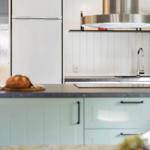 Küche mit weißen Schränken, Kühlschrank und Edelstahl-Armatur.