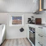 Küche mit weißen Schränken, Edelstahlherd und Fenstern.