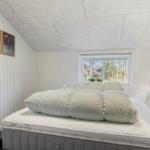 Schlafzimmer mit Bett, Fenster und Wandbildern.