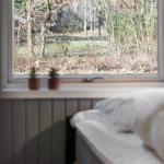 Ein Bett vor einem Fenster mit Blick auf einen Wald.