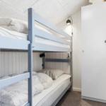 Zimmer mit Doppelstockbett, weißer Schrank und Wandlampe.