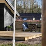 Hinter einem roten Schaukelhängematt steht eine Terrasse mit Tisch und Stühlen.