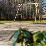 Holzschaukel mit zwei Sitzplätzen auf einer Terrasse im Garten.