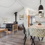 Wohn- und Essbereich mit Holzboden, schwarzer Couch und Esstisch mit Tischdecke.