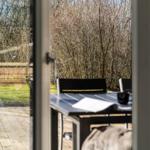 Terrasse mit Tisch und Stühlen, Blick in einen bewaldeten Garten.