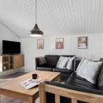 Wohnzimmer mit schwarzer Couch, Holztisch und TV an der Wand.