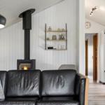 Schwarzes Ledersofa vor Kamin mit Holzregal und weißen Wänden.