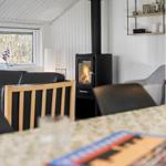 Wohnraum mit Kaminofen, Tisch, Stühlen und Fenster.