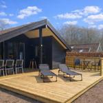 Holzterrasse mit Liegen, Tischen und Stühlen vor einem modernen Holzhaus.