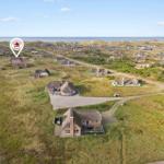 Haus mit Dach aus Stroh auf einer grünen Wiese, Blick auf das Meer.