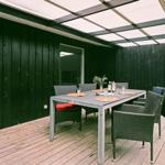 Terrasse mit Tisch und Stühlen unter Dach