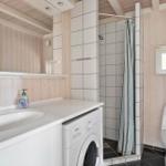 Badezimmer mit Dusche, Waschmaschine und Toilette.