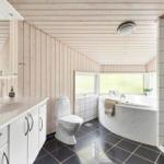 Badezimmer mit Dusche, Badewanne und Toilette. Holzwände und Fliesenboden.