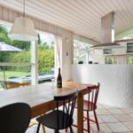 Essbereich mit Holztisch und Stühlen, Küche mit Kücheninsel und Blick auf Garten.