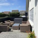 Terrasse mit Sitzgruppe, Tisch und Holzdecke. Hintergrund: Wohnhäuser und Hecke.