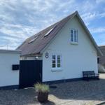 Wohnhaus mit Dachfenstern, schwarzer Tür und Bank auf Kiesfläche.