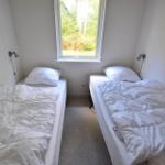 Zwei Betten mit weißen Bettwäschen und einem Fenster mit Blick auf Grün.