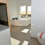 Bad mit Toilette, Waschbecken und Whirlpool unter Fenster