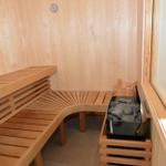 Sauna mit Holzbank, Steinkasten und Uhr an der Wand.