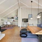 Wohnraum mit Holzfußboden, Kamin, Sofa und Esstisch. Küche im Hintergrund.