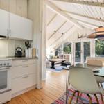 Küche mit Essbereich und Blick in Wohnzimmer mit Holzboden und großen Fenstern.